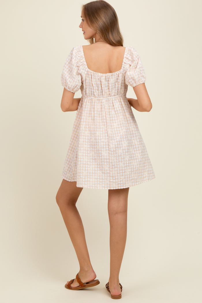 woman wearing a pastel checkered short sleeve maternity dress with a square neckline and gathered waist, showing her back