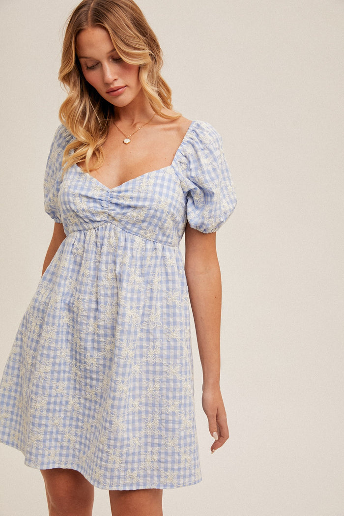 woman wearing a light blue checkered puff sleeve mini dress with a sweetheart neckline and gathered waist