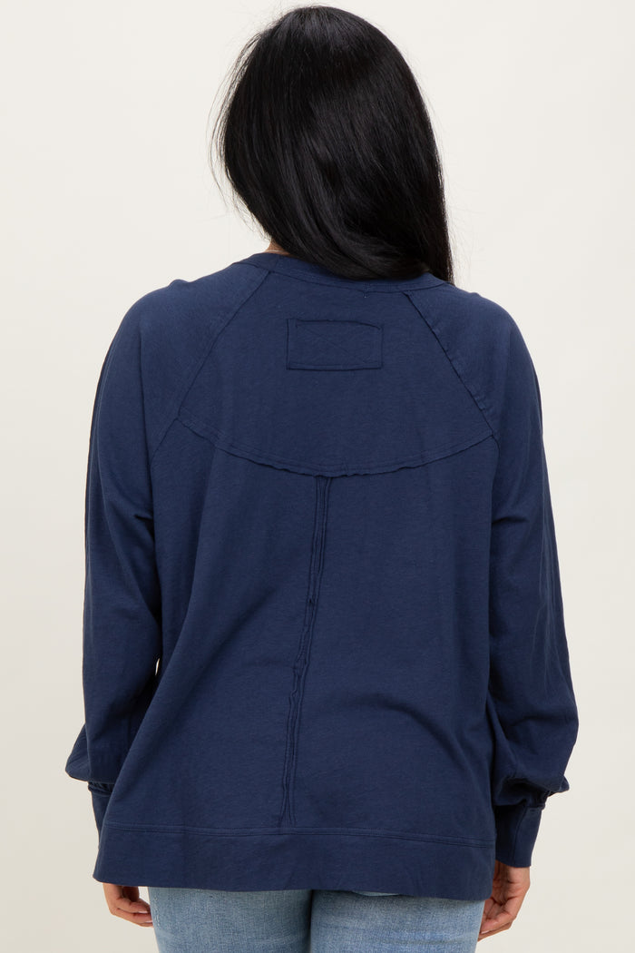 woman wearing a navy blue long sleeve top with a relaxed fit and unique seam detailing on the back