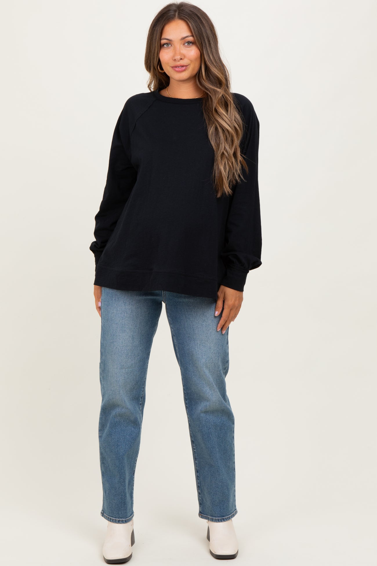 woman wearing a black maternity sweatshirt with long sleeves and casual blue jeans