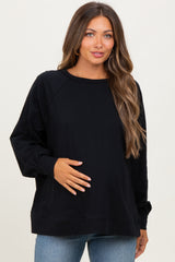 woman wearing a black long sleeve maternity top and holding her baby bump