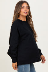 woman wearing a black oversized maternity sweatshirt with a visible baby bump and casual jeans