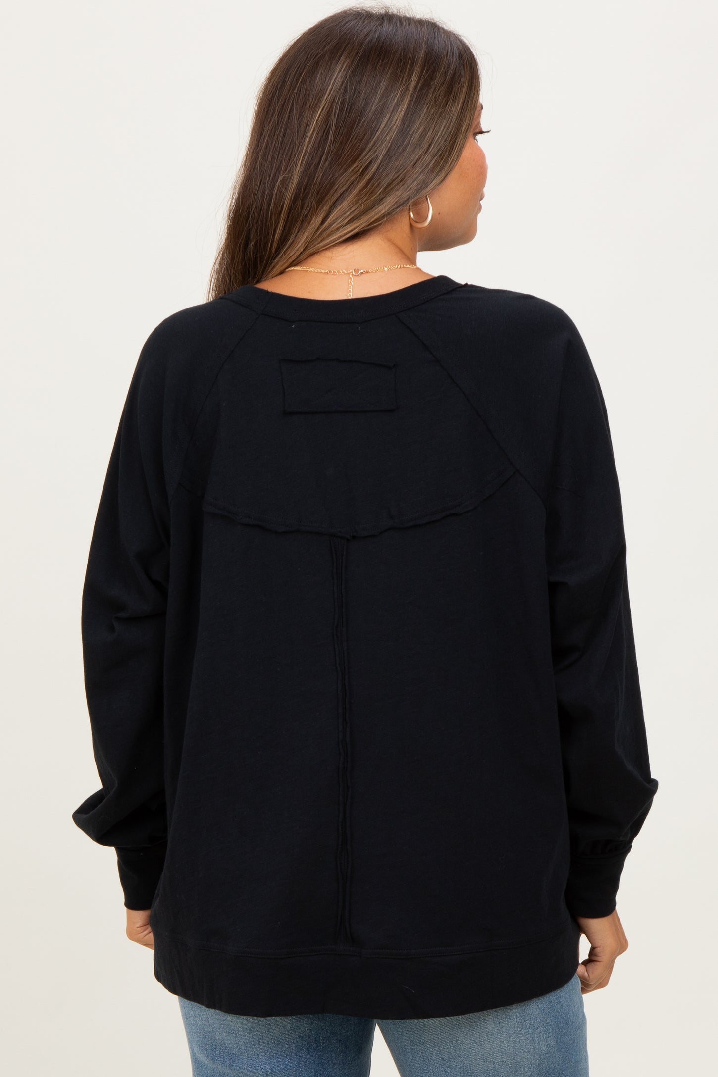 woman wearing a black maternity sweatshirt with a relaxed fit and subtle stitching details, viewed from the back