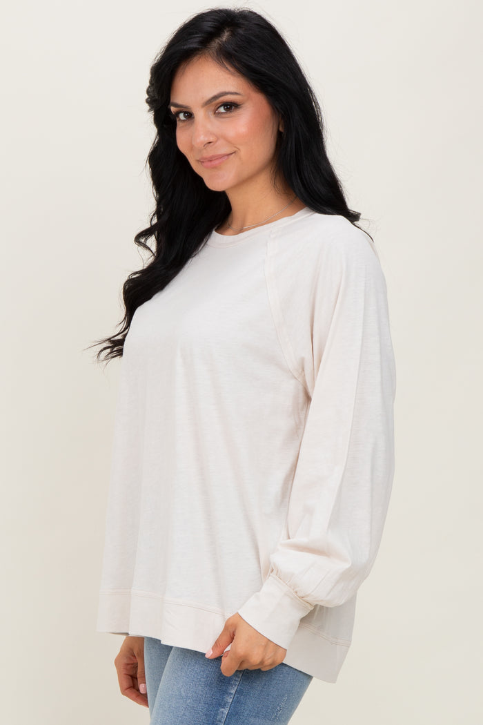 woman wearing a light beige long sleeve top with relaxed fit and balloon sleeves paired with blue jeans