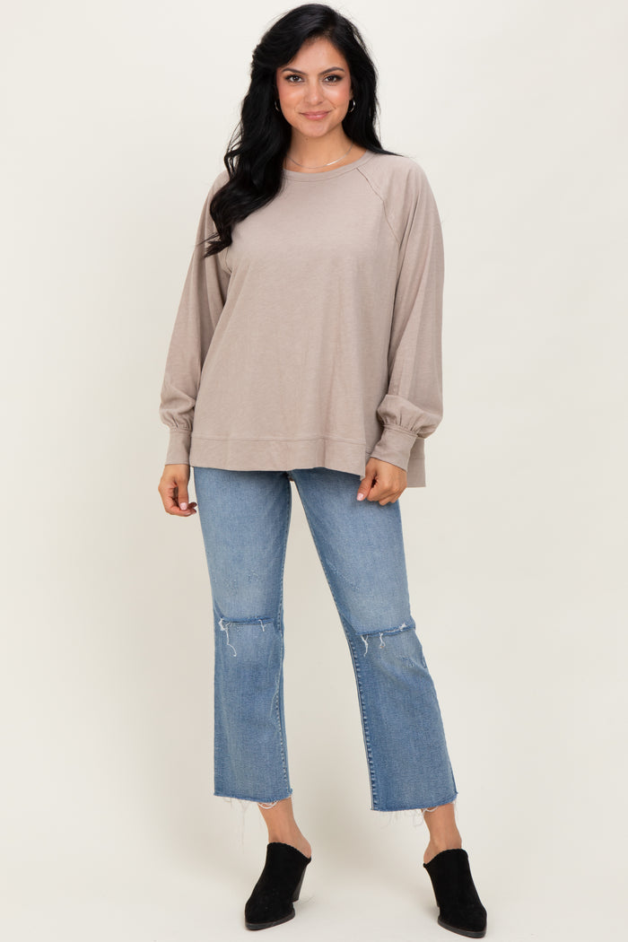 woman wearing a beige long sleeve loose top with balloon sleeves paired with light blue cropped jeans and black mules