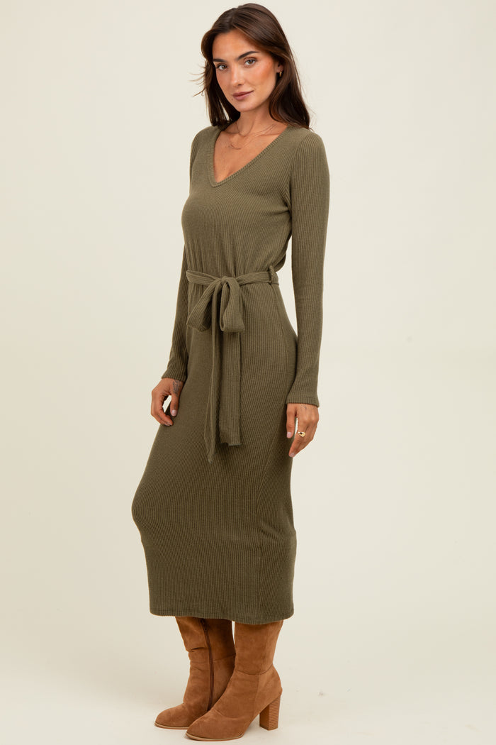 woman wearing a long olive green ribbed knit dress with a tie waist and long sleeves, paired with brown heeled boots