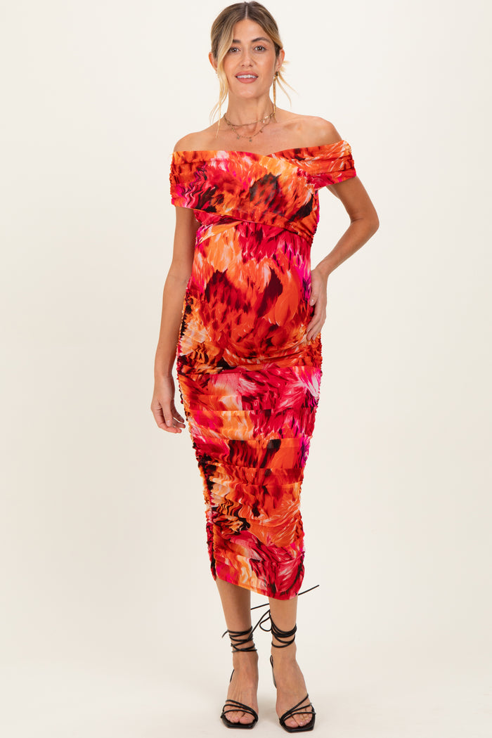 woman wearing a vibrant orange and pink floral off-the-shoulder maternity dress with a visible baby bump