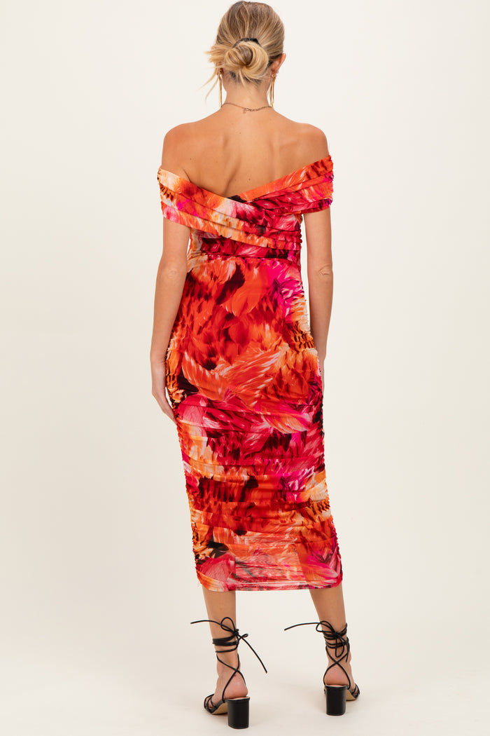 woman wearing a vibrant off-the-shoulder maternity dress with floral print, showing a baby bump from the back