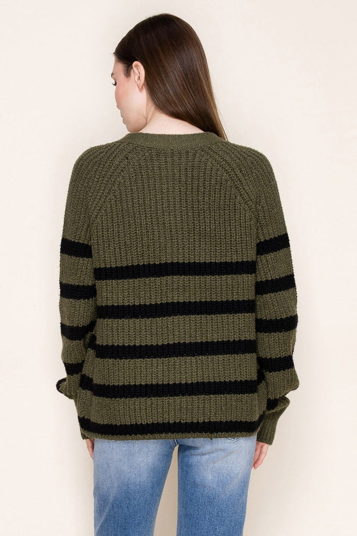 woman wearing an olive green striped sweater with black stripes, shown from the back