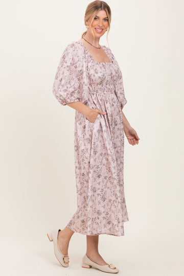 woman wearing a light pink floral midi dress with puff sleeves and pockets