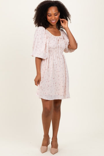 woman wearing a light pink floral print short dress with puff sleeves and a cinched waist