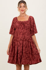 woman wearing a rust colored floral print maternity dress with square neckline and puff sleeves