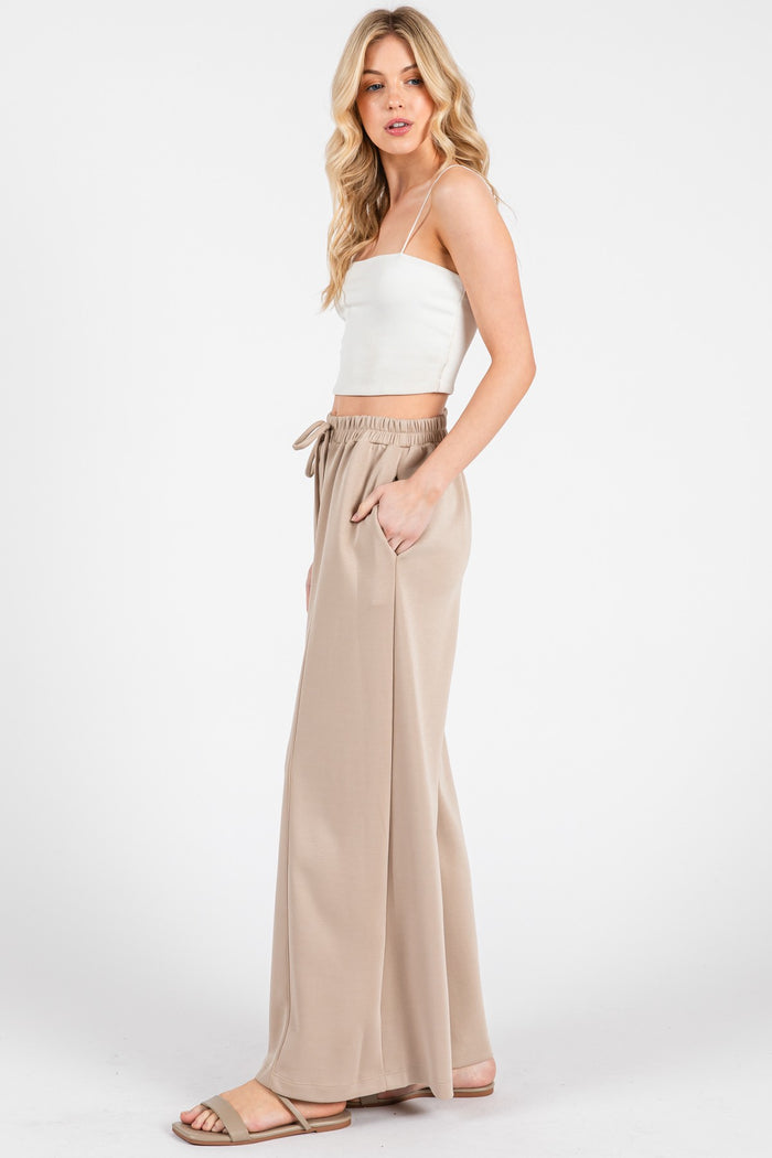 woman wearing a white ribbed crop top and beige wide-leg pants with an elastic waistband and side pockets