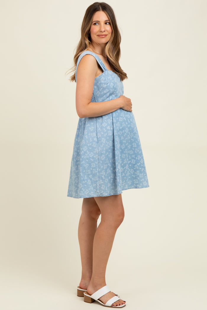 woman wearing a light blue maternity sundress with floral print and holding her baby bump