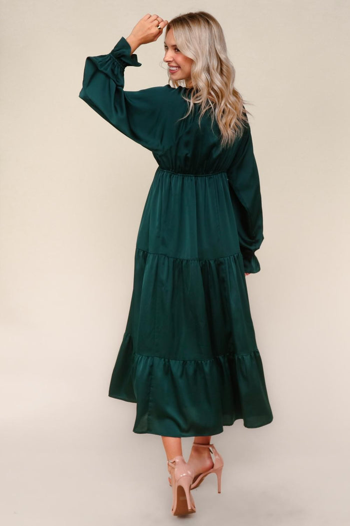 woman wearing a teal long sleeve tiered maxi dress, showing a back view with a cinched waist and ruffled hem