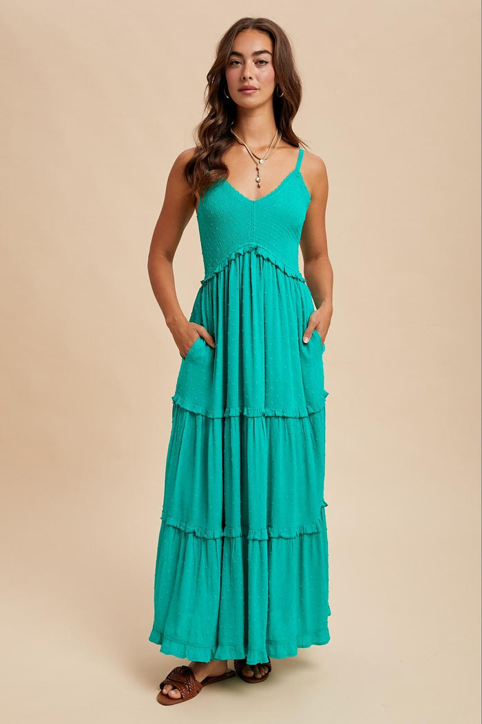 woman wearing a teal tiered maxi dress with adjustable straps and side pockets