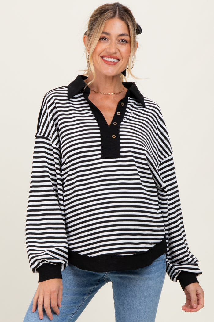 woman wearing a black and white striped maternity sweatshirt with a collar and button detail, smiling at the camera