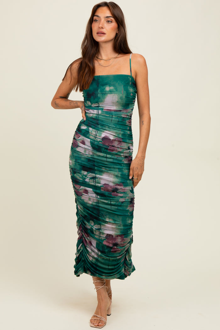 woman wearing a green and purple floral print bodycon midi dress with ruching and spaghetti straps