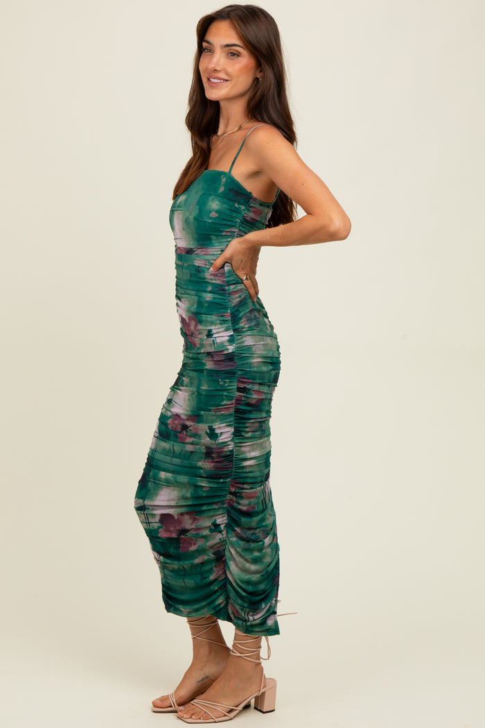 woman wearing a green tie-dye midi dress with adjustable straps and ruching details