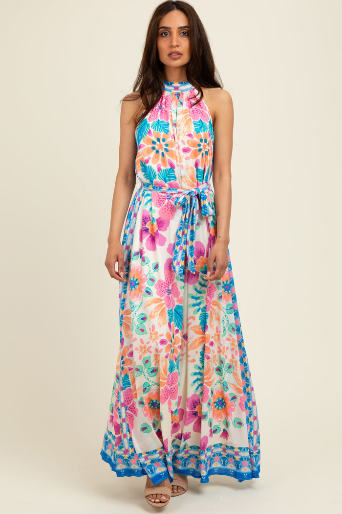 woman wearing a colorful floral maxi dress with a halter neck and tie waist detail
