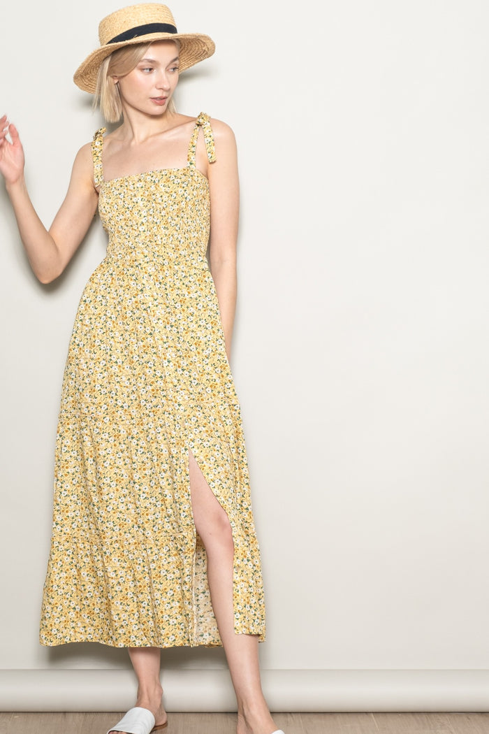 woman wearing a yellow floral maxi dress with tie straps and a side slit