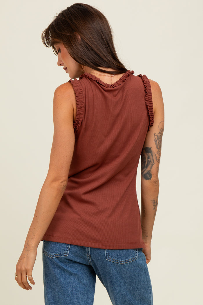 woman wearing a rust-colored sleeveless top with ruffled shoulder details and styled with blue jeans
