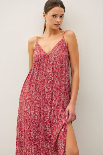 woman wearing a red paisley maxi dress with spaghetti straps and a high side slit