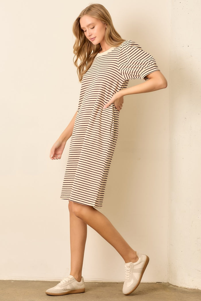 woman wearing a striped beige and brown oversized t-shirt dress with side pockets and white sneakers