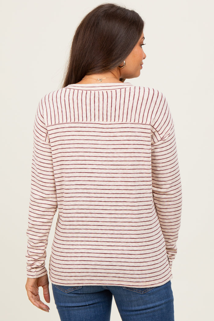 woman wearing a striped maternity top with long sleeves, showing the back view and soft pink and burgundy colors