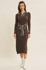 woman wearing a brown ribbed midi dress with a collar and white trim, cinched at the waist with a matching belt