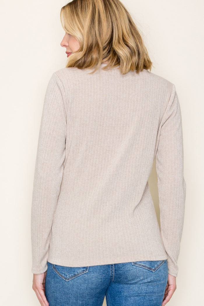 woman wearing a beige ribbed long sleeve top with a round neckline, seen from the back, paired with blue jeans