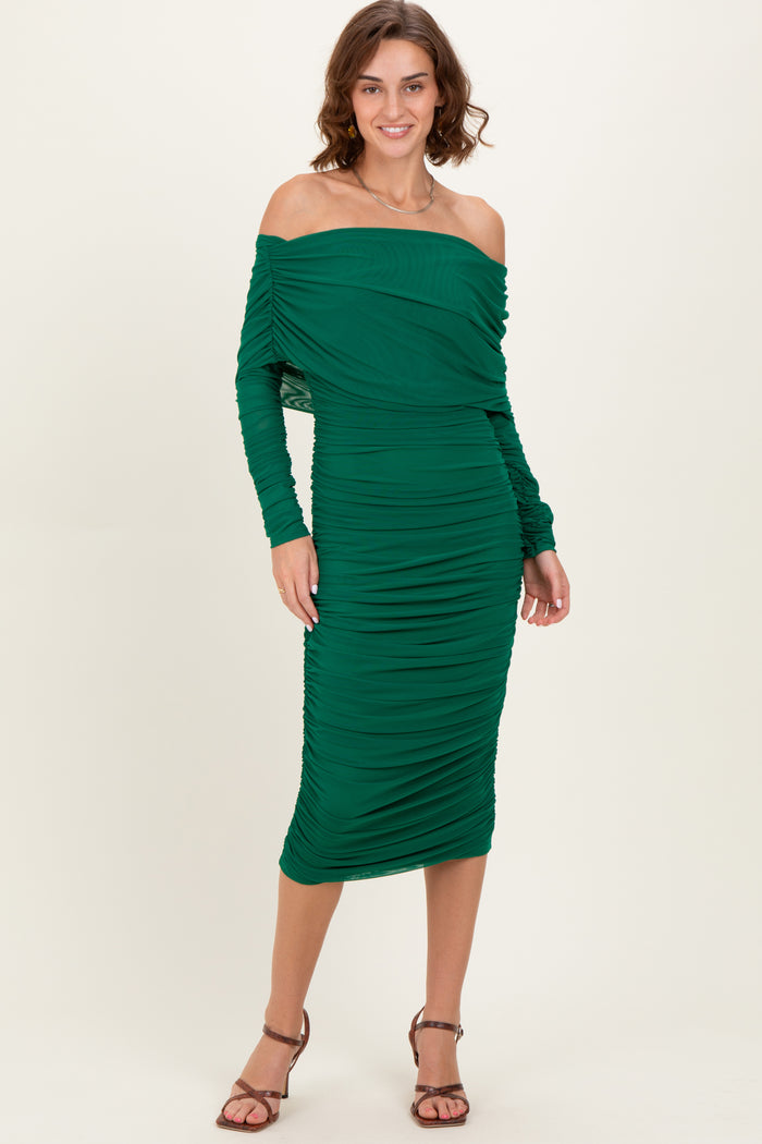 woman wearing a green off-the-shoulder ruched midi dress with long sleeves and a fitted silhouette