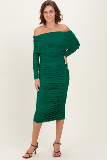woman wearing a green off-shoulder midi dress with ruched detailing and long sleeves, standing in a relaxed pose