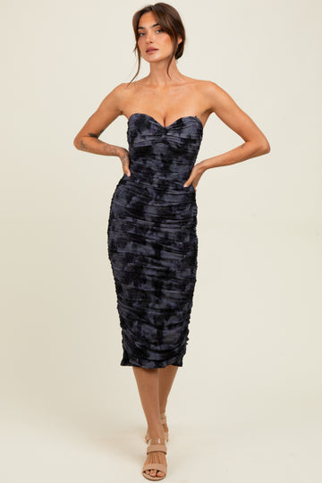 woman wearing a strapless navy blue fitted midi dress with ruching details and a sweetheart neckline