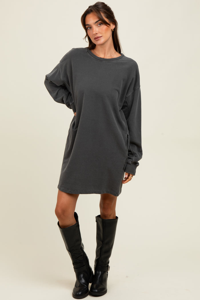 woman wearing a gray oversized sweatshirt dress with long sleeves and side pockets, paired with black knee-high boots