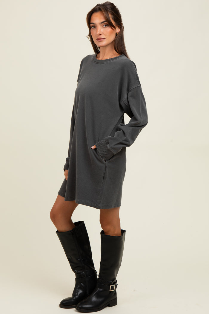 woman wearing a gray long sleeve sweatshirt dress with side pockets and knee-high black leather boots