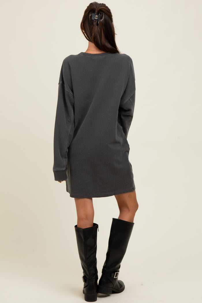 woman wearing a dark grey oversized sweatshirt dress and tall black knee-high boots, facing away from the camera