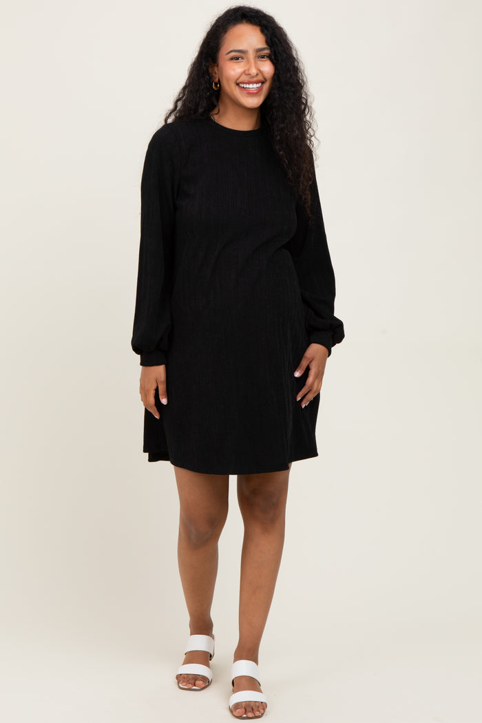 woman wearing a black long sleeve maternity dress with ribbed texture and loose fit, showcasing her baby bump