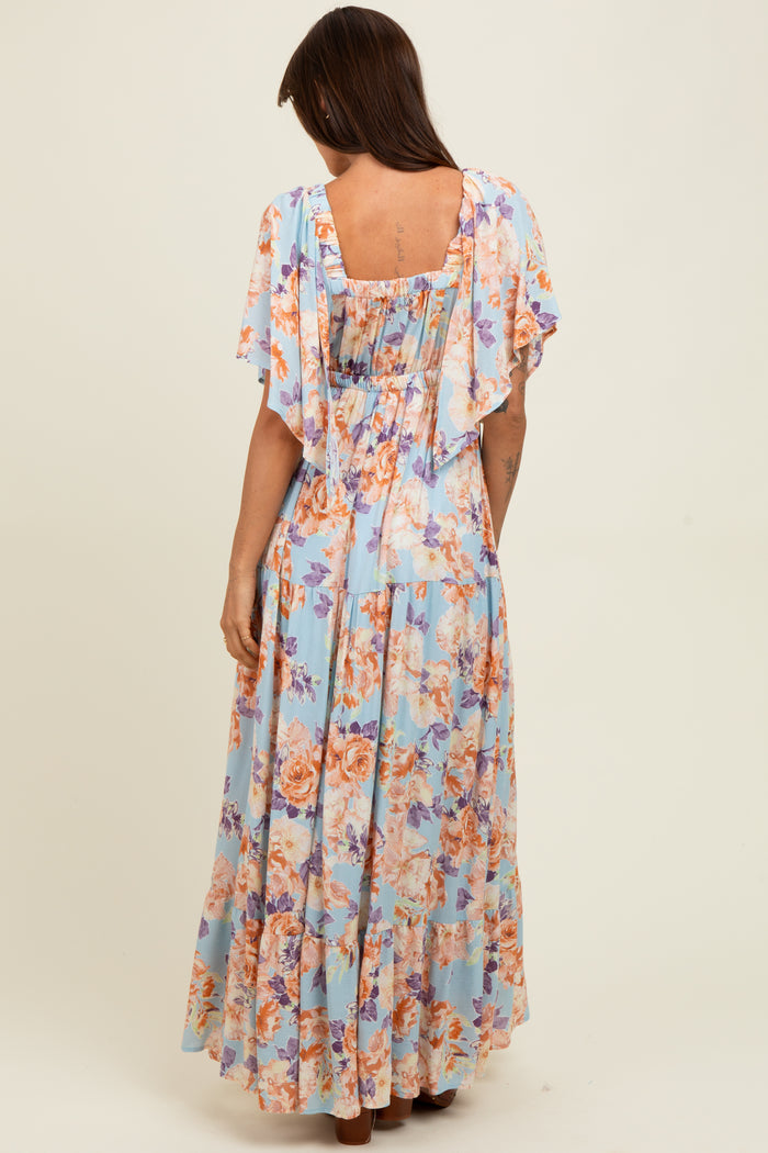 woman wearing a floral maxi dress in light blue with flutter sleeves and a ruched back design