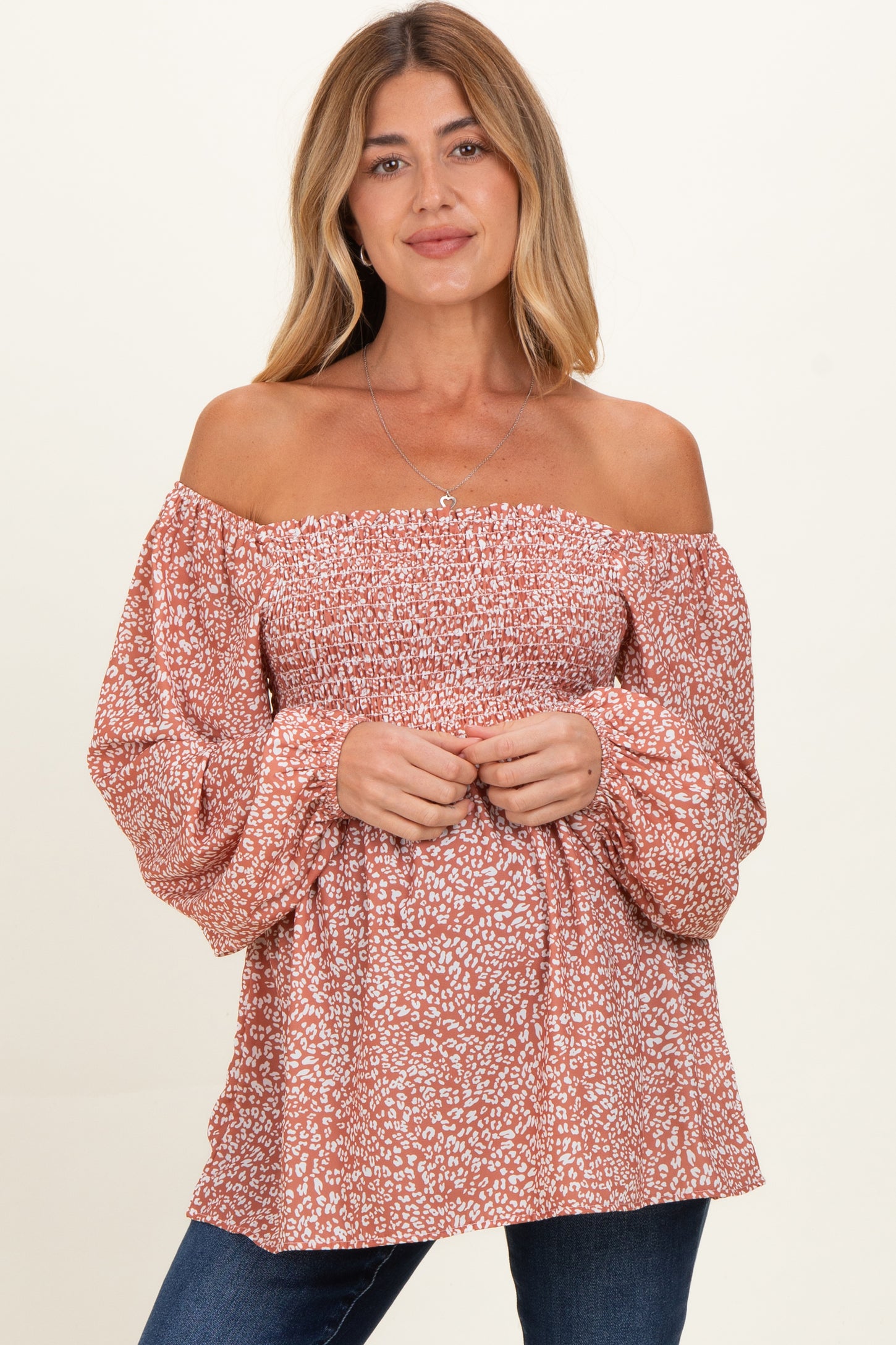 woman wearing a rust off-the-shoulder maternity top with puff sleeves and floral print