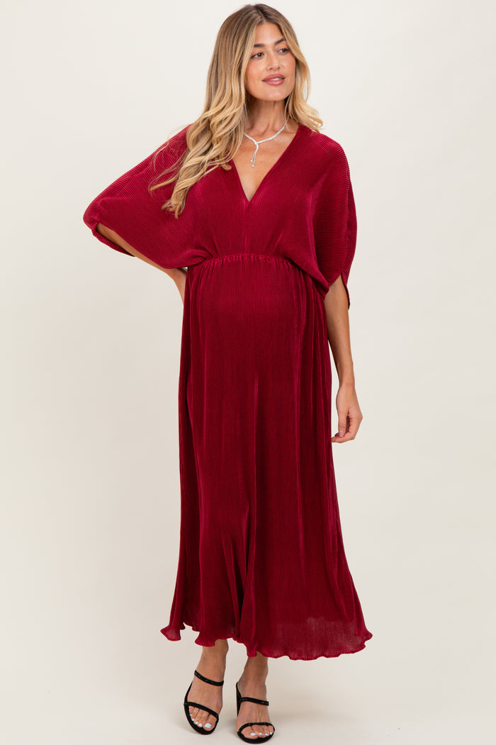 woman wearing a deep red maternity dress with a flowy design and a v-neckline, showcasing her baby bump