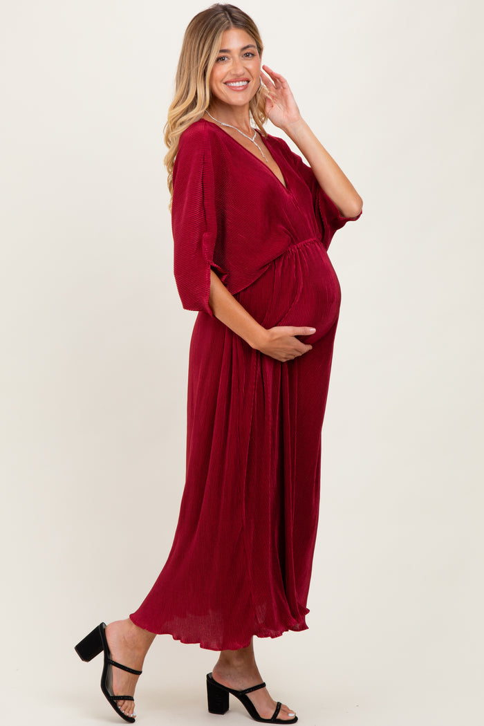 woman wearing a burgundy maternity wrap dress and holding her baby bump