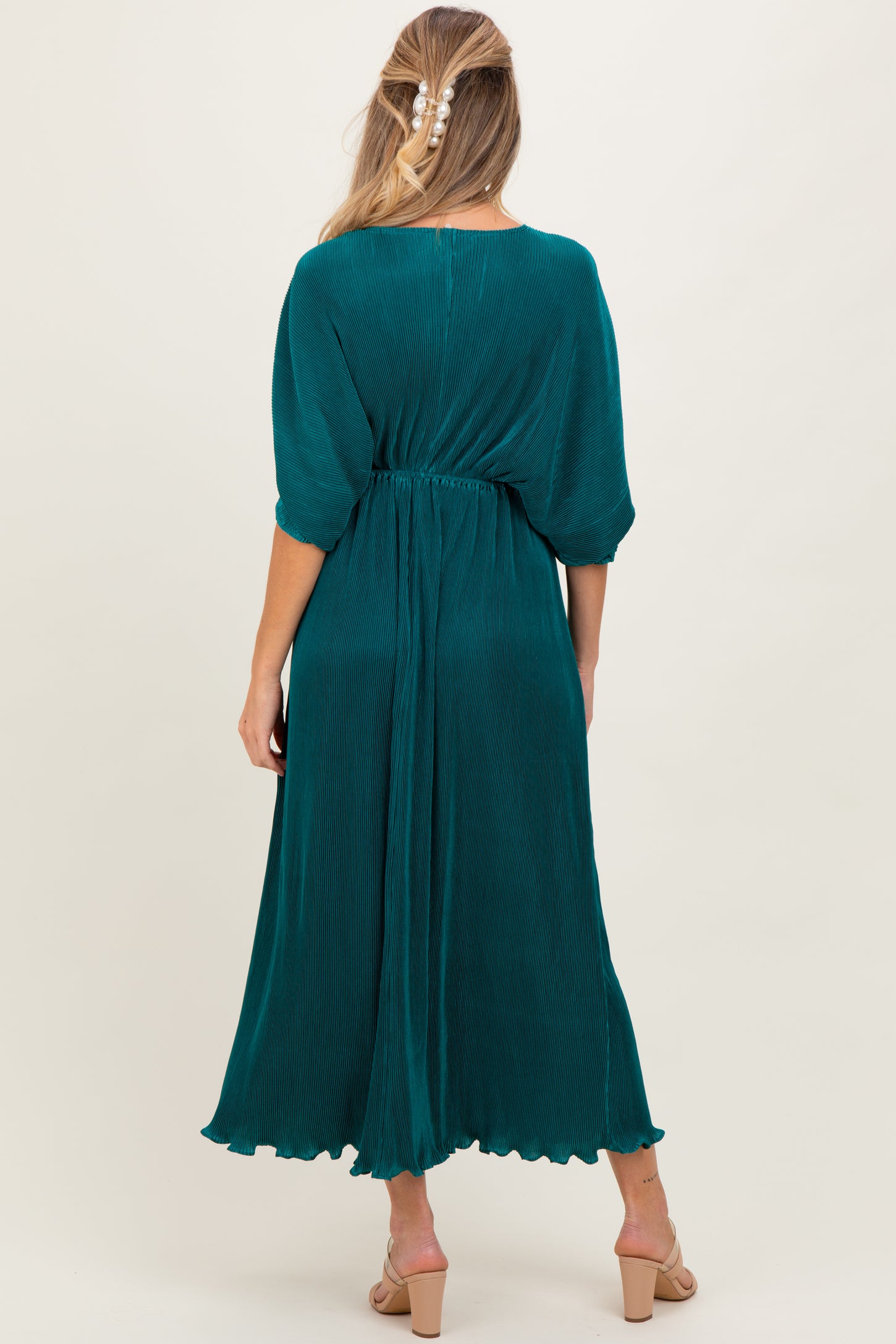 woman wearing a teal maternity dress with half sleeves and an elastic waist, showing a flowing silhouette from the back