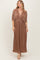 woman wearing a brown pleated maxi dress with a deep v-neck and short sleeves.