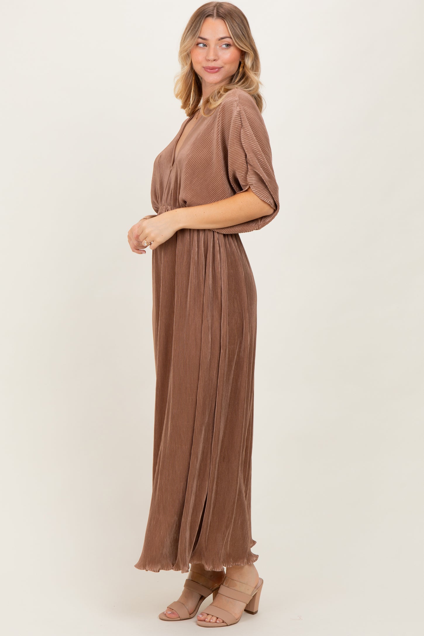 woman wearing a brown pleated maxi dress with short sleeves and a v-neckline