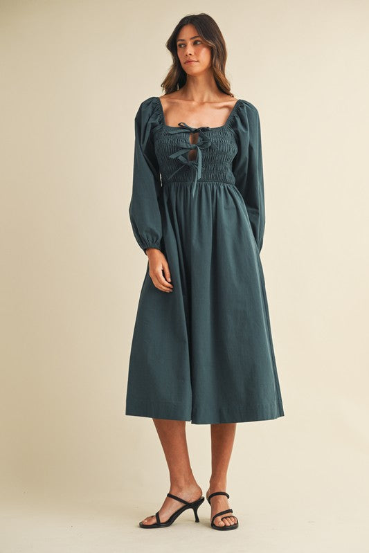 woman wearing a dark teal long sleeve smocked midi dress with a square neckline and puffed sleeves