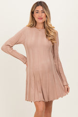 woman wearing a soft pink ribbed maternity dress with long sleeves and a flared skirt, showcasing her baby bump