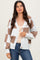 woman wearing a cream and brown checkered oversized cardigan over a beige top and blue jeans