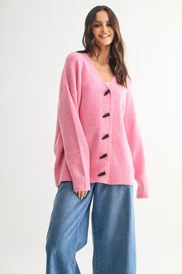woman wearing a pink oversized cardigan with buttons and relaxed fit, paired with wide-leg jeans