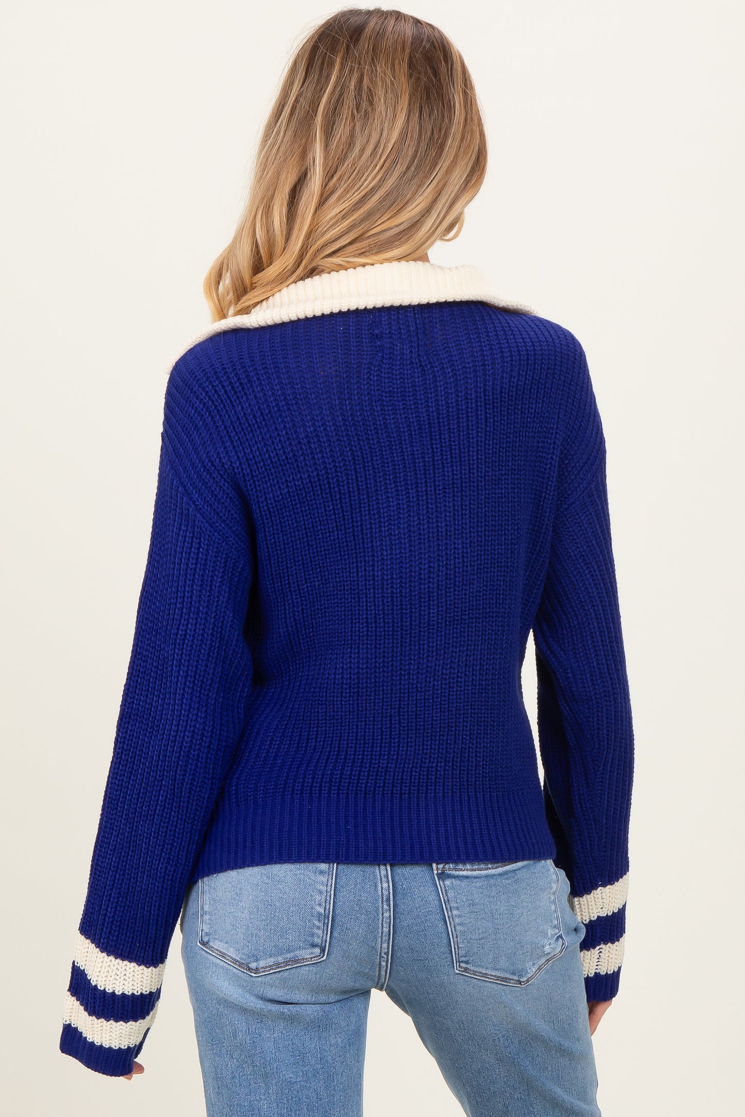 woman wearing a navy blue maternity sweater with white striped details on the sleeves and a relaxed fit
